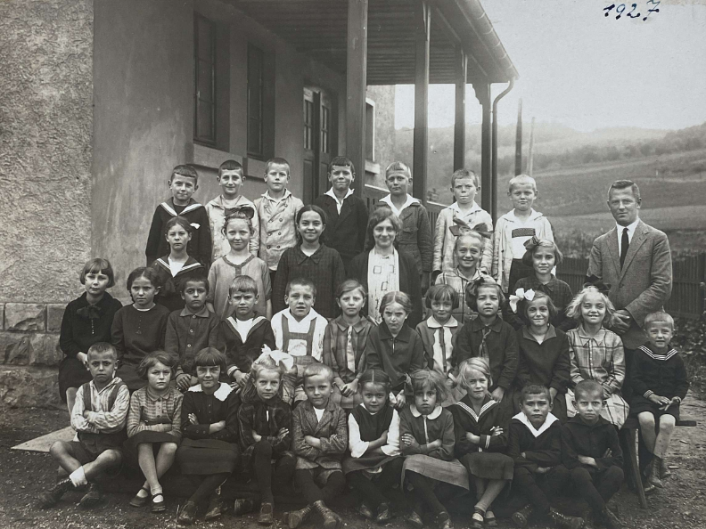 schwarz-weiße Aufnahme von Kindern vor dem alten Schulhaus